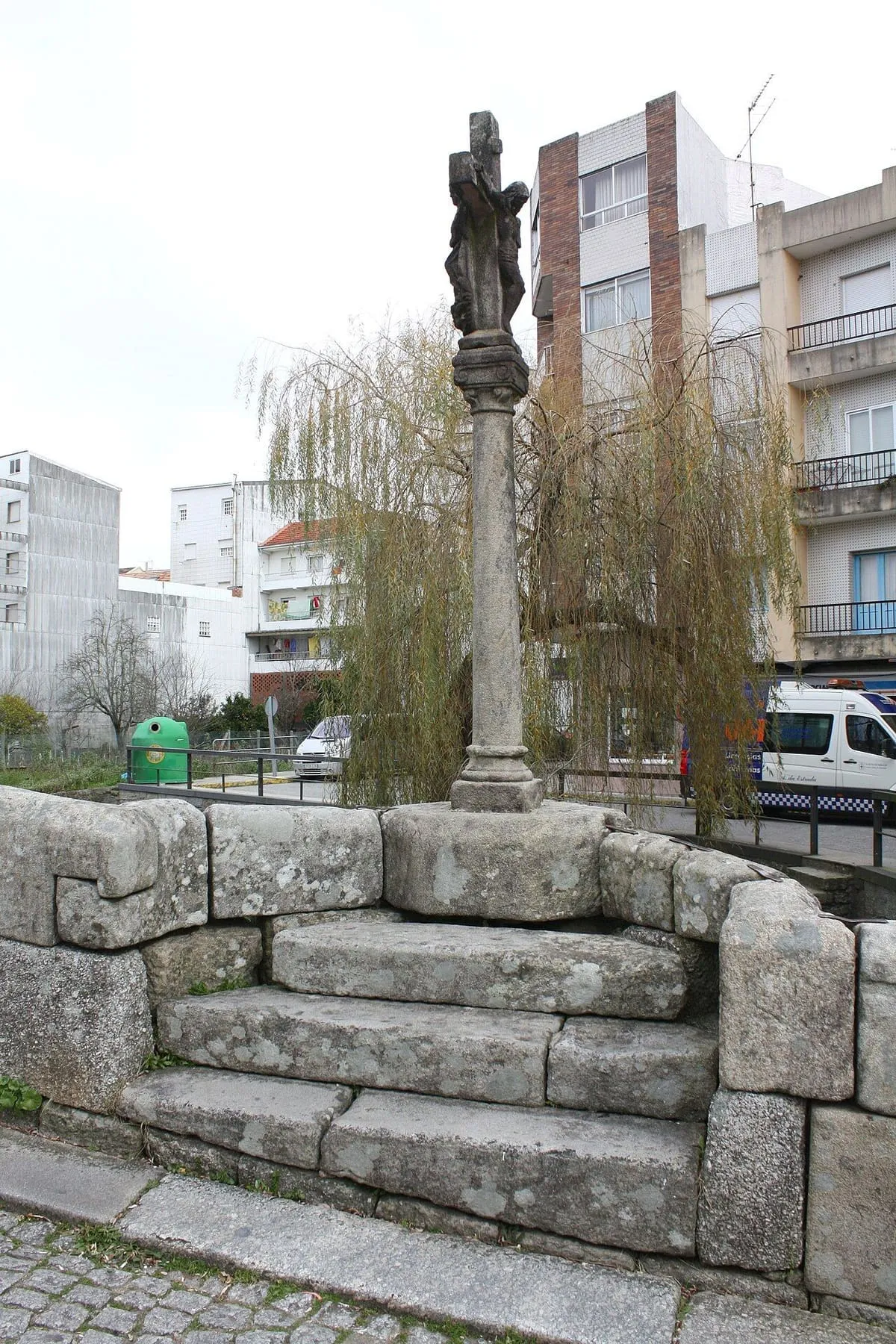 El cruceiro sobre el apartadero triangular de la ponte da Bermaña, entre bancos de piedra