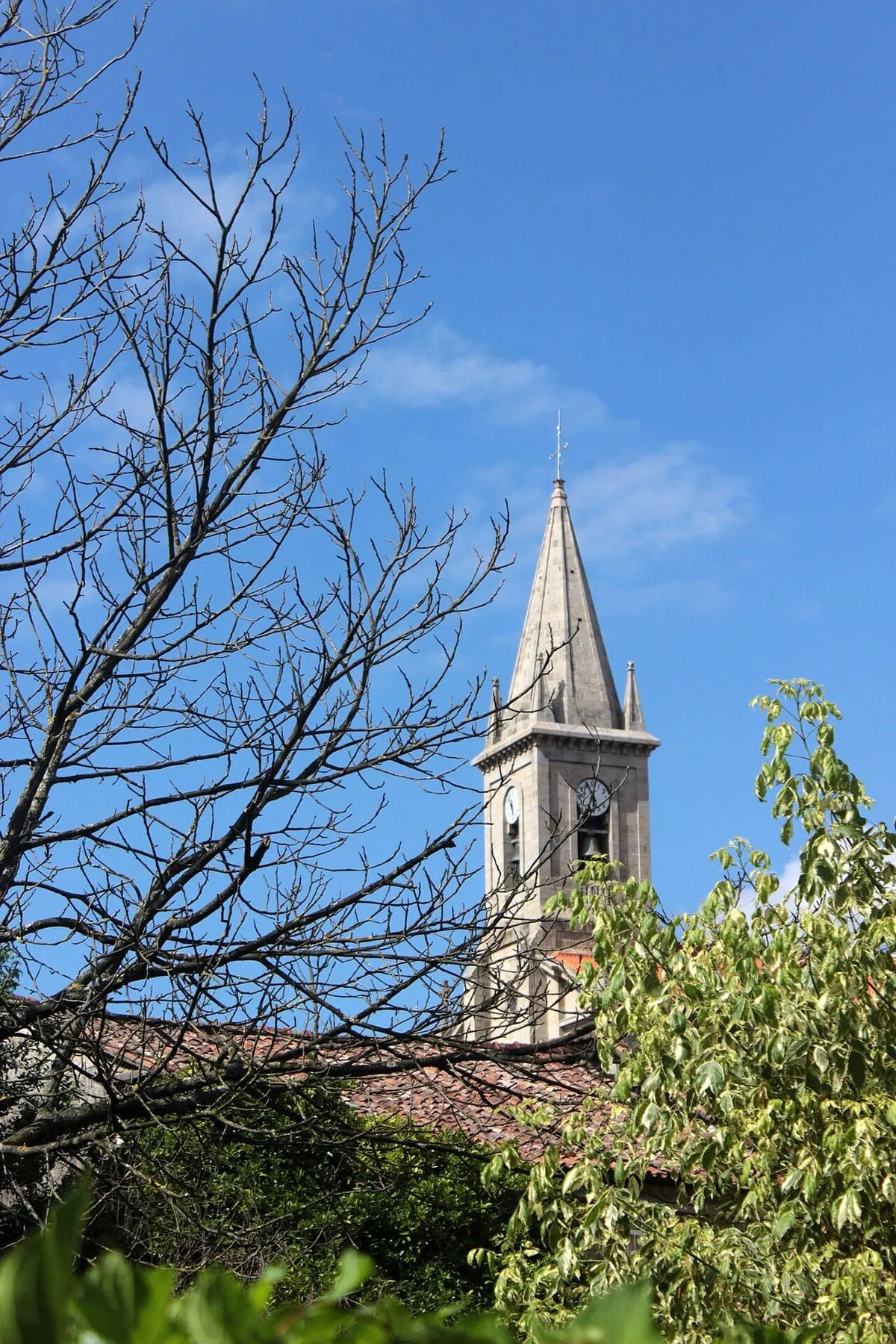 La torre con aguja de la iglesia de Santo Tomé sobre un cielo azul