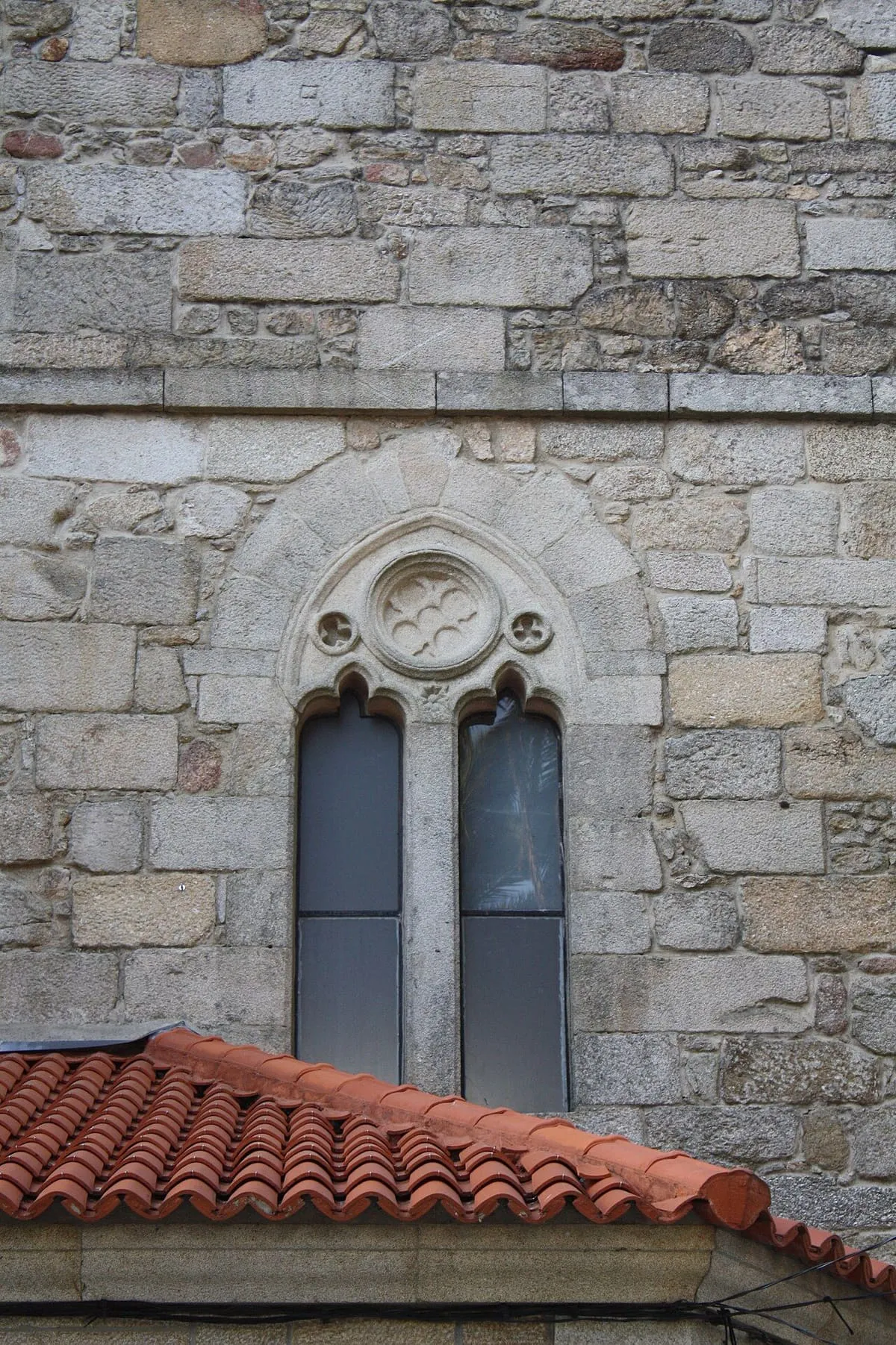 Dos ventanas apuntadas gemelas con un rosetón encima, en un muro de sillería de la iglesia de Santo Tomé