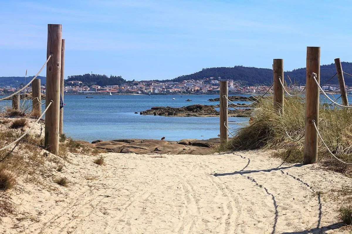 Camino de arena con postes de madera que baja a una playa del Carreirón