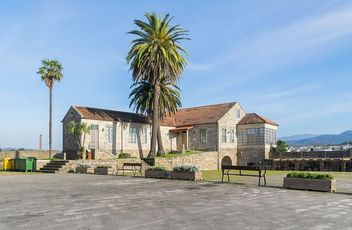 Casa del Conde y otras casas de piedra con tejado de teja entre palmeras, dentro del recinto de Salvaterra