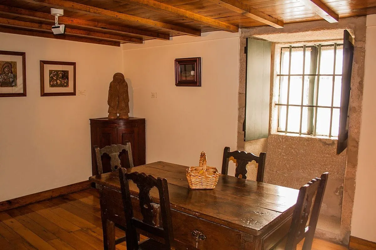 Sala con mesa, sillas y suelo de madera en la casa-museo de Rosalía de Castro