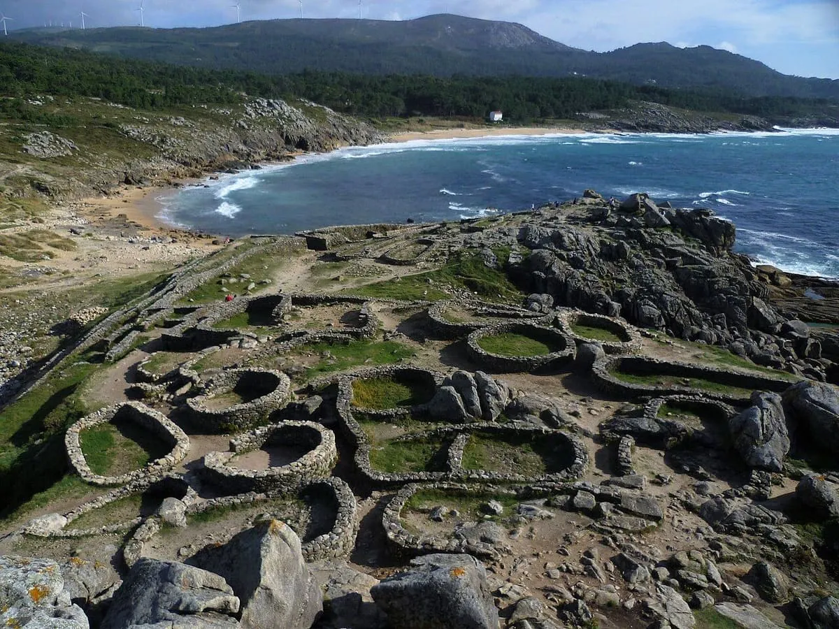 El castro de Baroña con sus casas circulares y la playa de Areia Longa detrás