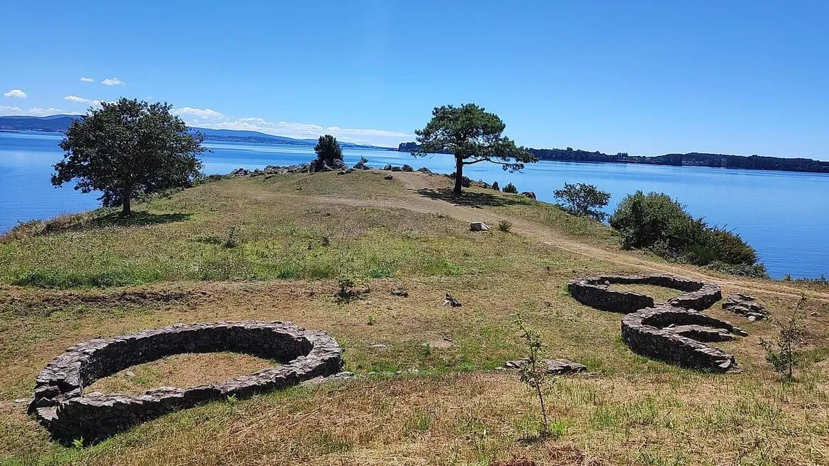 Base circular de piedra del Castro Pequeño de Neixón, con la ría de Arousa y pinos al fondo