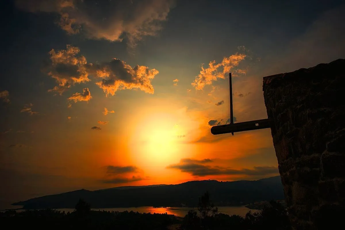 Puesta de sol rojiza detrás de las aspas de un molino de viento sobre la ría