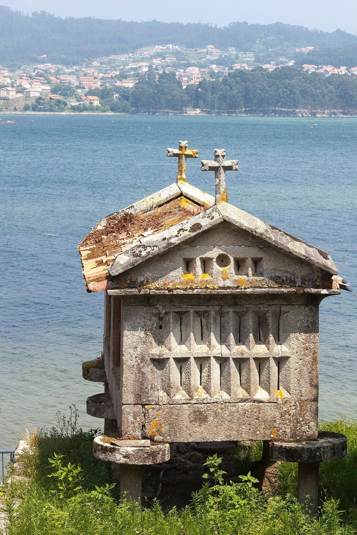 Hórreo de piedra con cruces en el remate, junto al agua de la ría de Pontevedra