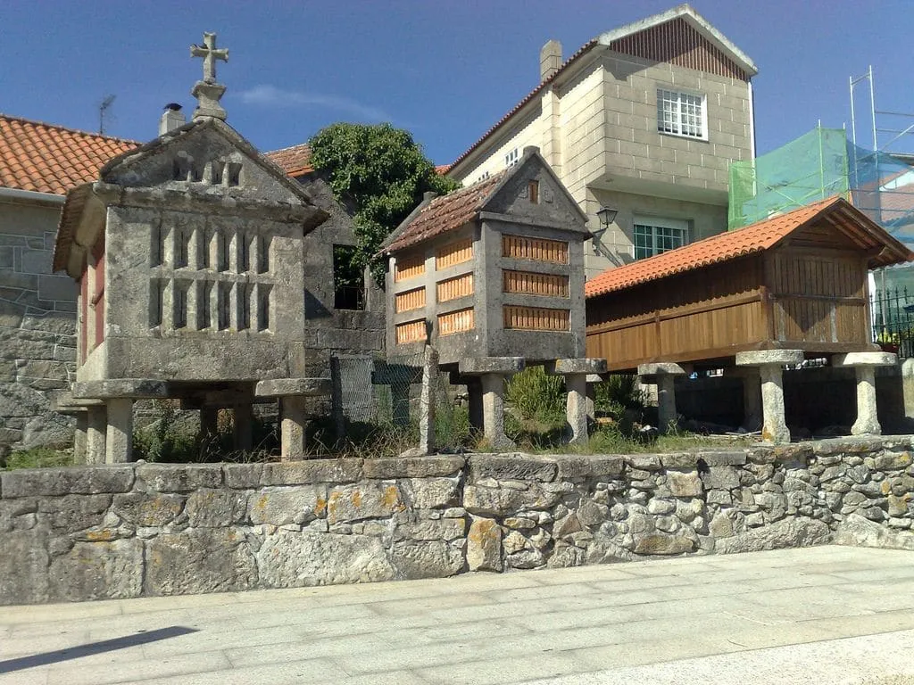 Varios hórreos de piedra y madera junto a una casa, en una calle de Combarro