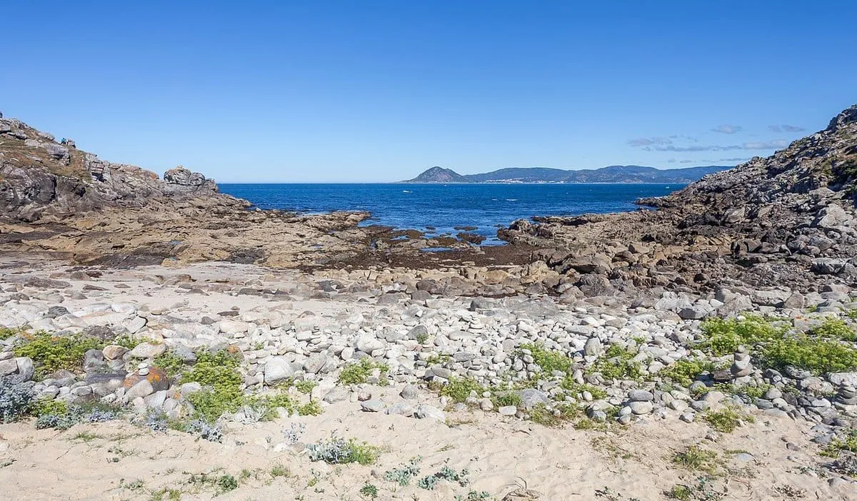 Rocas, arena y mar abierto vistos desde el castro, con la costa al fondo