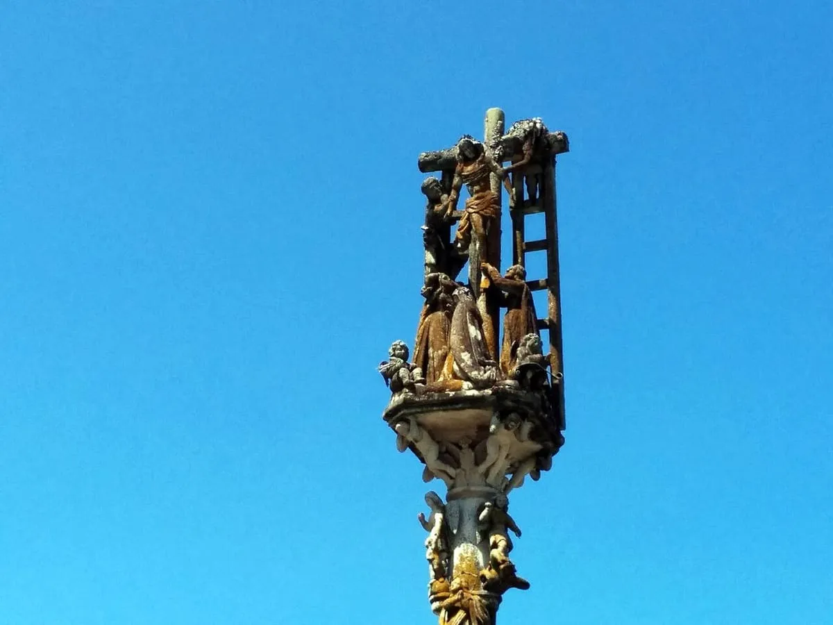 Remate del cruceiro de O Hío con el Descendimiento de Cristo y la escalera, contra un cielo azul