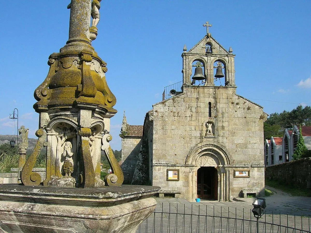 Base tallada del cruceiro junto a la fachada románica de la iglesia de San Andrés de O Hío