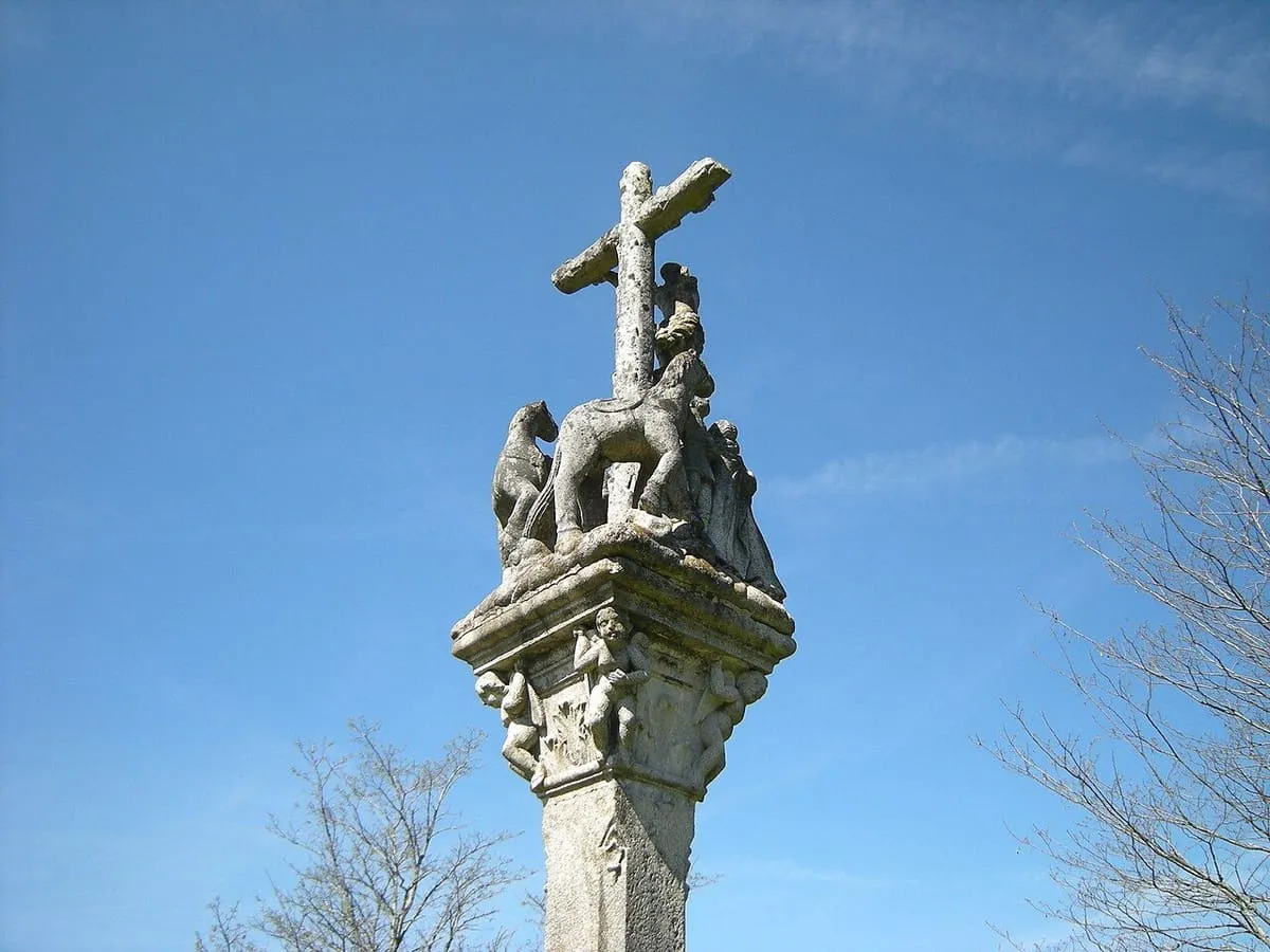 Cruceiro de piedra con el Crucificado, junto a la capilla del castro de Troña, contra el cielo azul