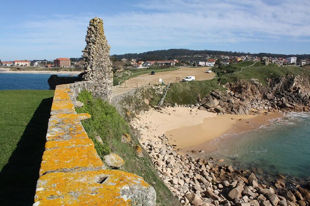 Muro de la ermita de A Lanzada sobre una cala de arena y rocas