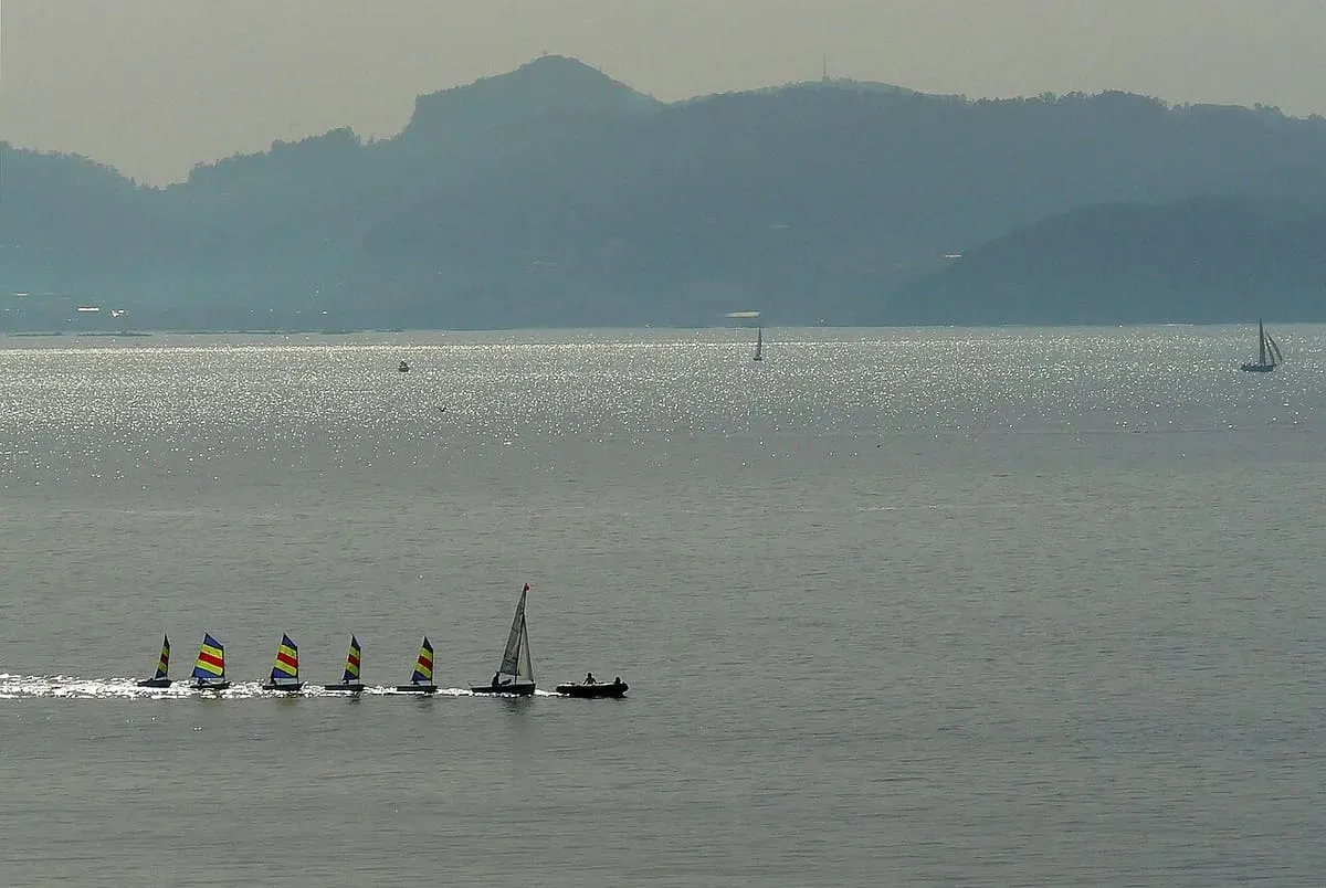 Embarcaciones de vela ligera de una escuela náutica navegando en fila en la ría de Pontevedra