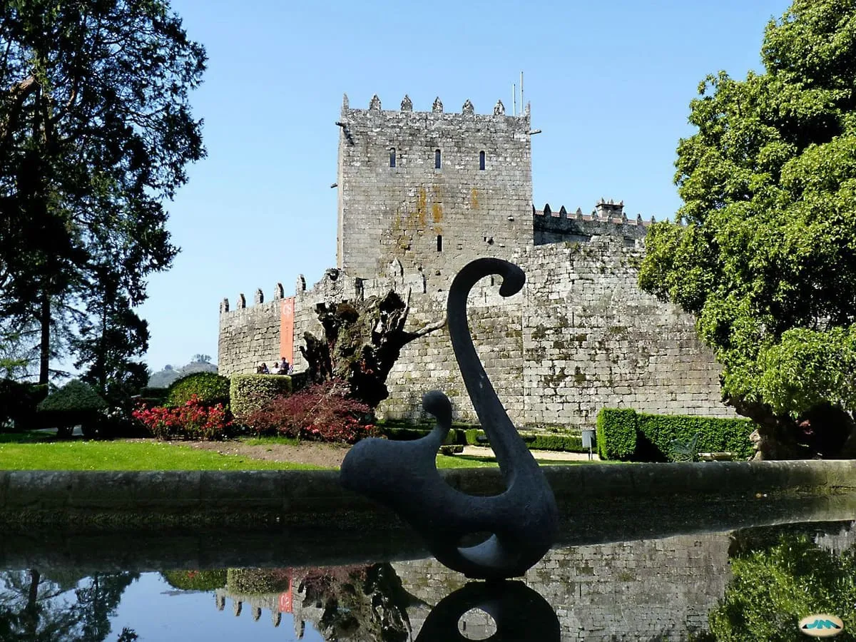 Estanque del jardín con una escultura oscura, un castaño seco y la torre del homenaje al fondo