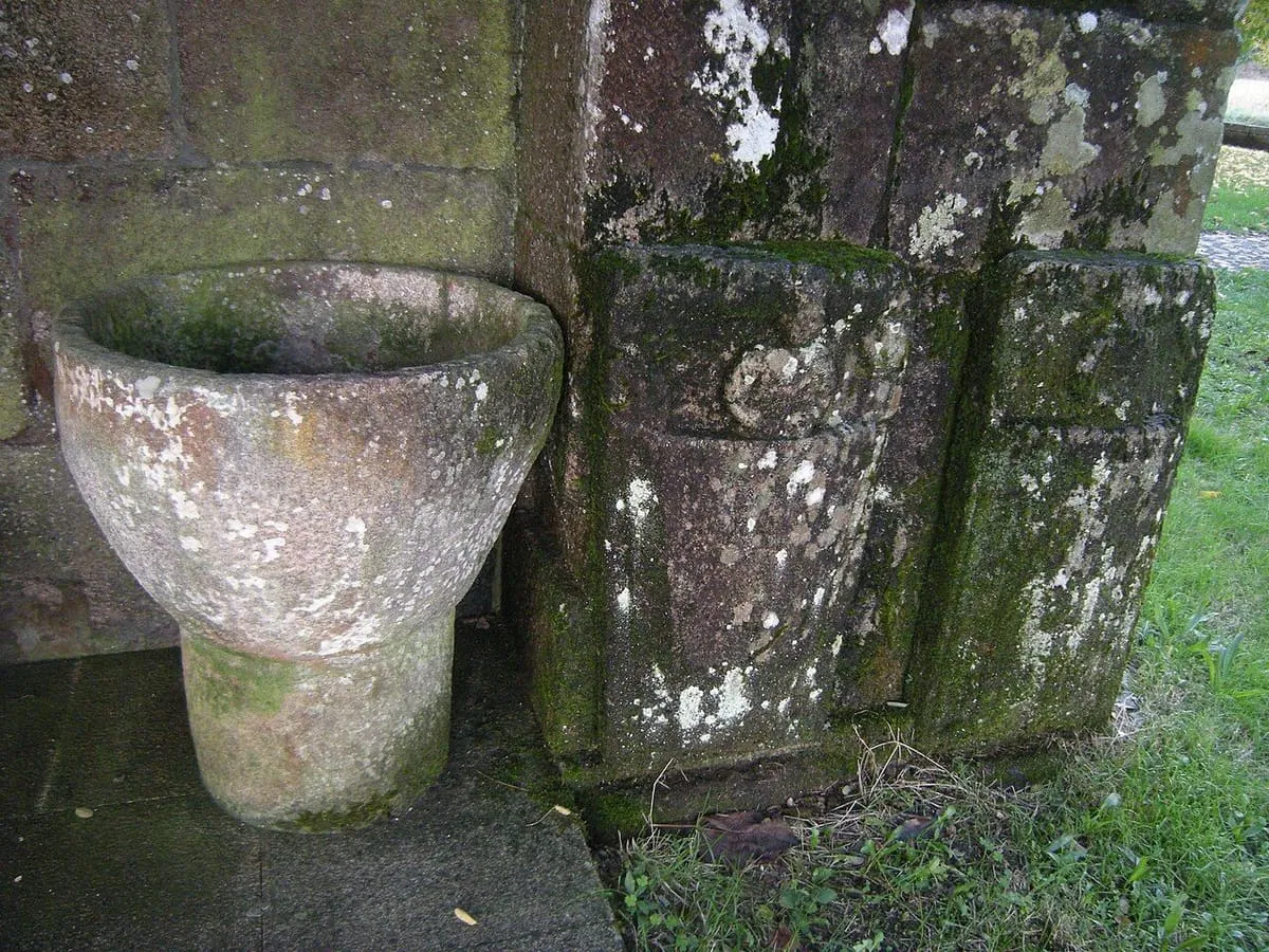 Una pila de piedra junto al muro de la iglesia de Ouzande