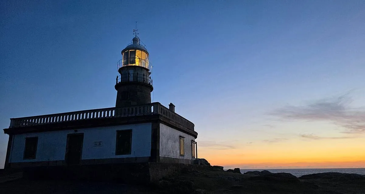 Linterna del faro de Corrubedo al anochecer, con el cielo naranja