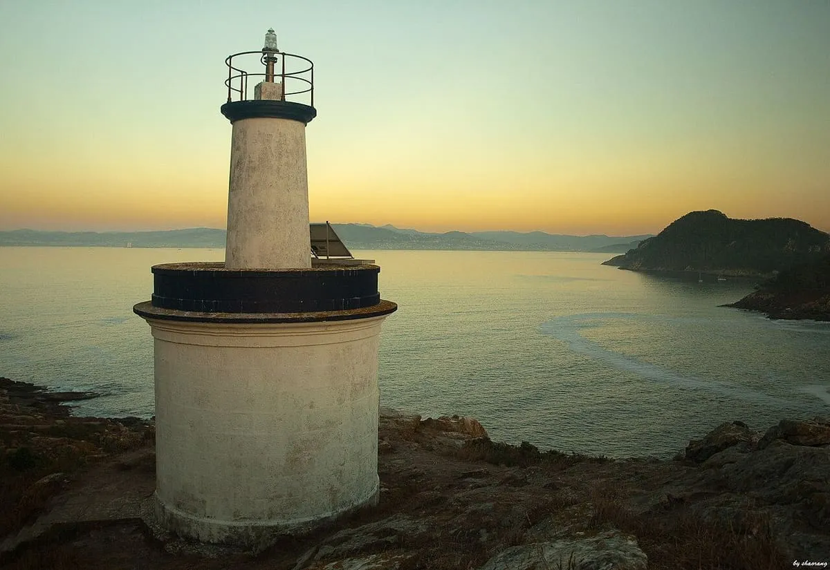 Faro da Porta al atardecer, con la costa de las islas Cíes al fondo