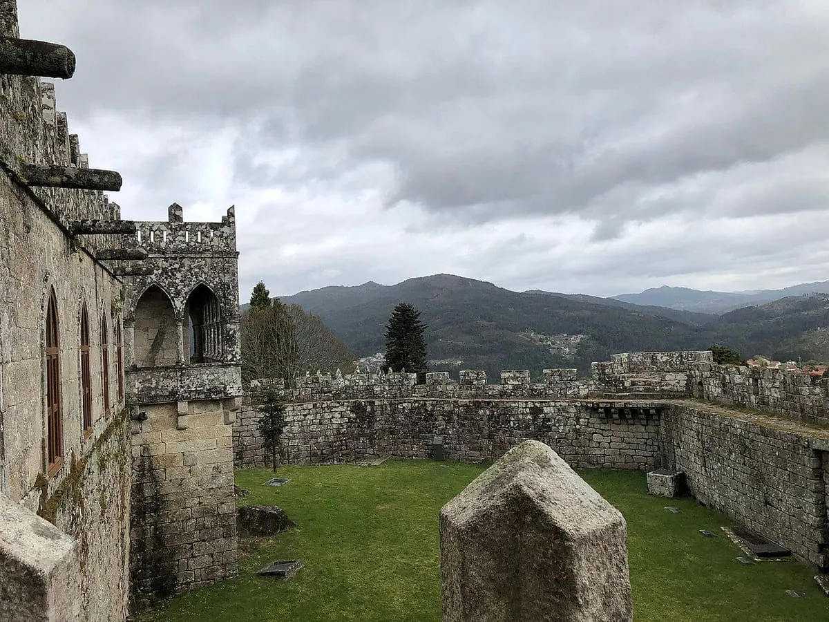Foso y murallas almenadas del castillo de Soutomaior, con los montes al fondo