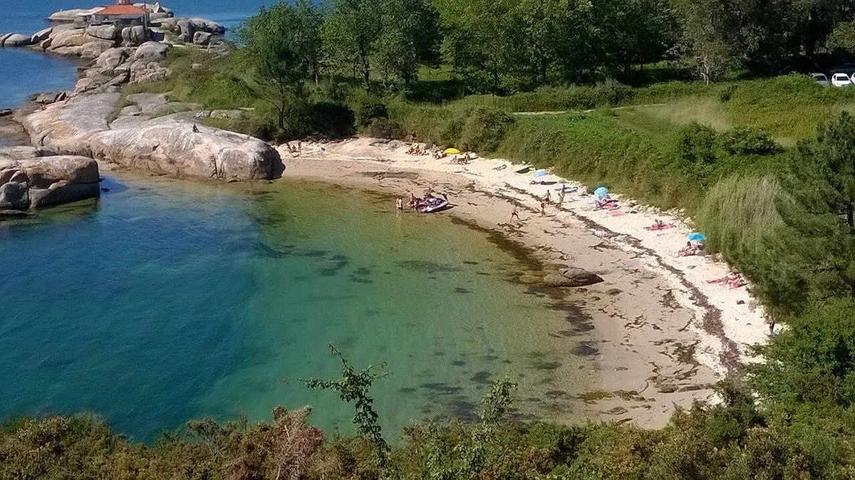 Playa de arena y rocas junto al agua clara de la ría, en la zona de Punta Cabalo
