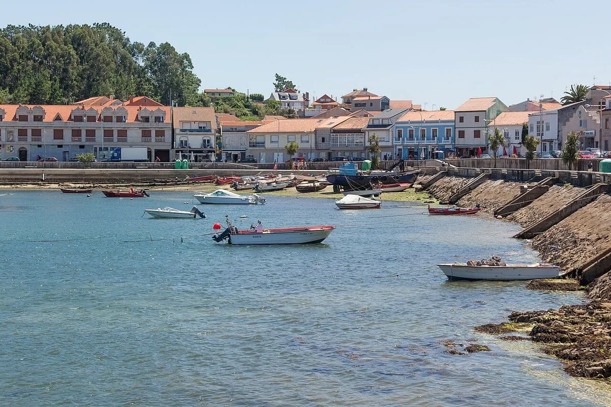 Paseo marítimo y casas de la Illa de Arousa asomadas a la ría, con barcas en la orilla