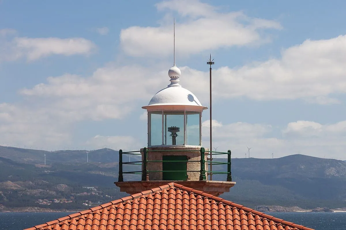 Linterna del faro del monte Louro sobre un tejado rojo, con la ría al fondo