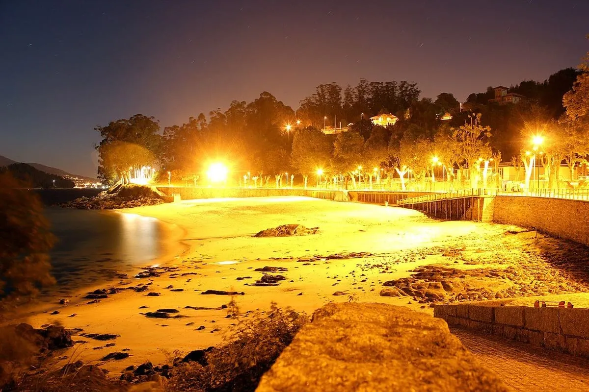 La playa de Portocelo de noche, con el paseo iluminado de luz naranja