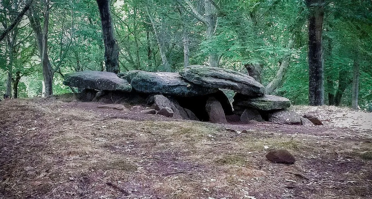 Vista lateral del dolmen con sus losas inclinadas y el monte al fondo