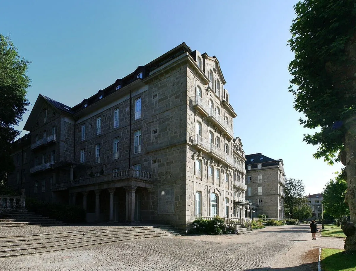 Marquesina de hierro y cristal sobre una entrada del Gran Hotel, con árboles del parque