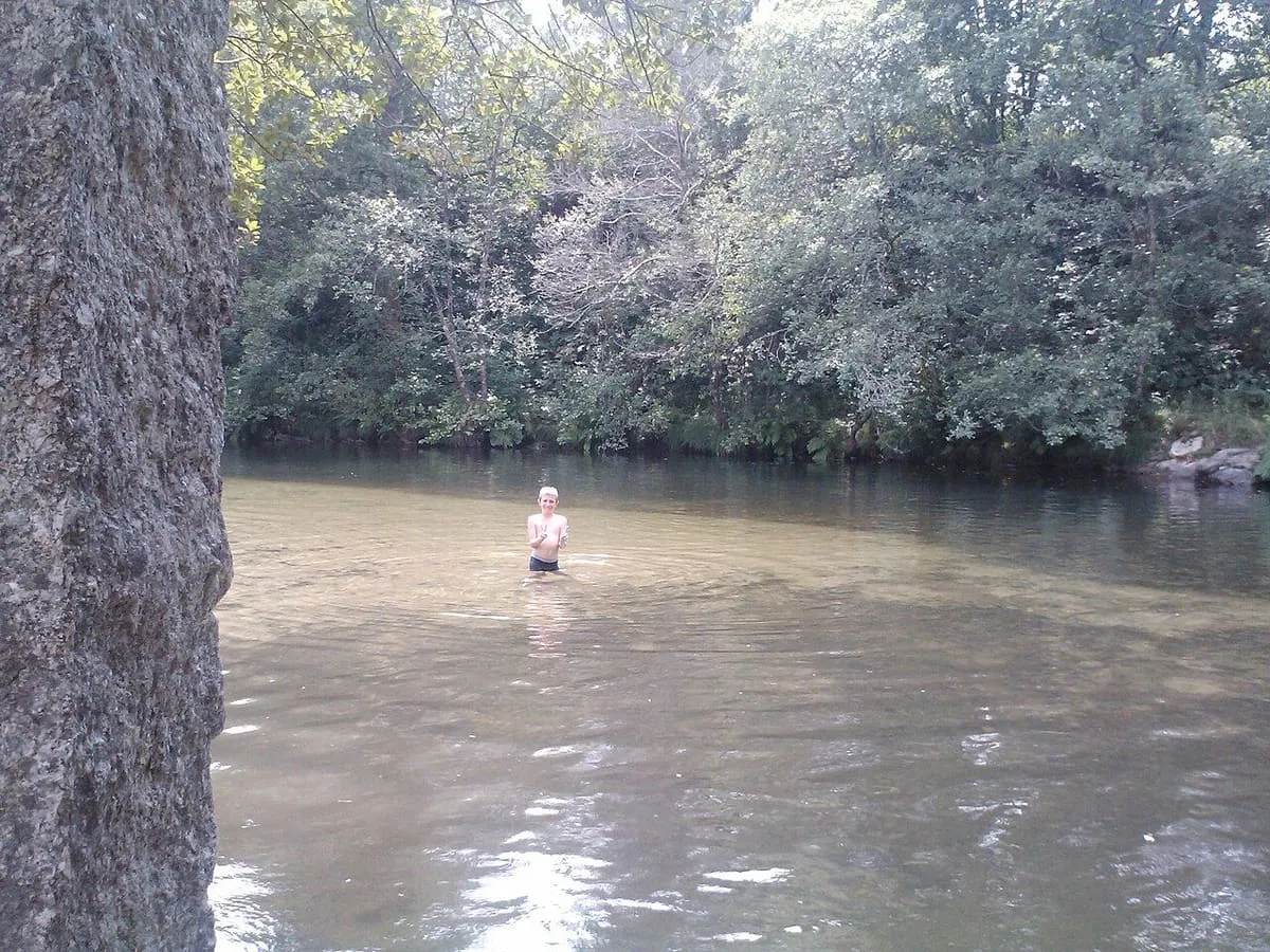 Bañista en una zona de baño del río Tea rodeada de árboles