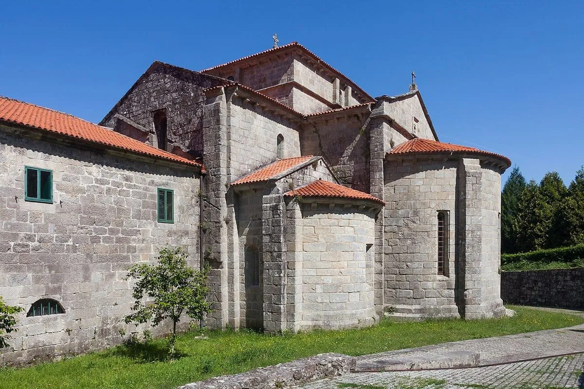 Ábside románico del monasterio de Armenteira, con tejados de teja bajo un cielo azul