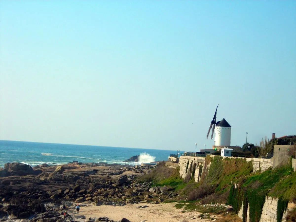 Costa rocosa de Mougás con un molino de viento blanco sobre un muro de piedra