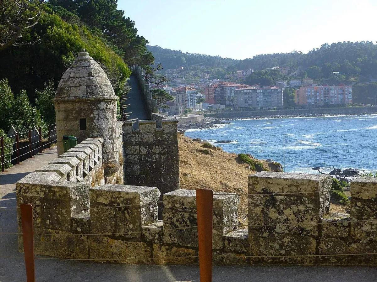 Garita de piedra sobre la muralla de Monterreal, con la villa de Baiona al fondo