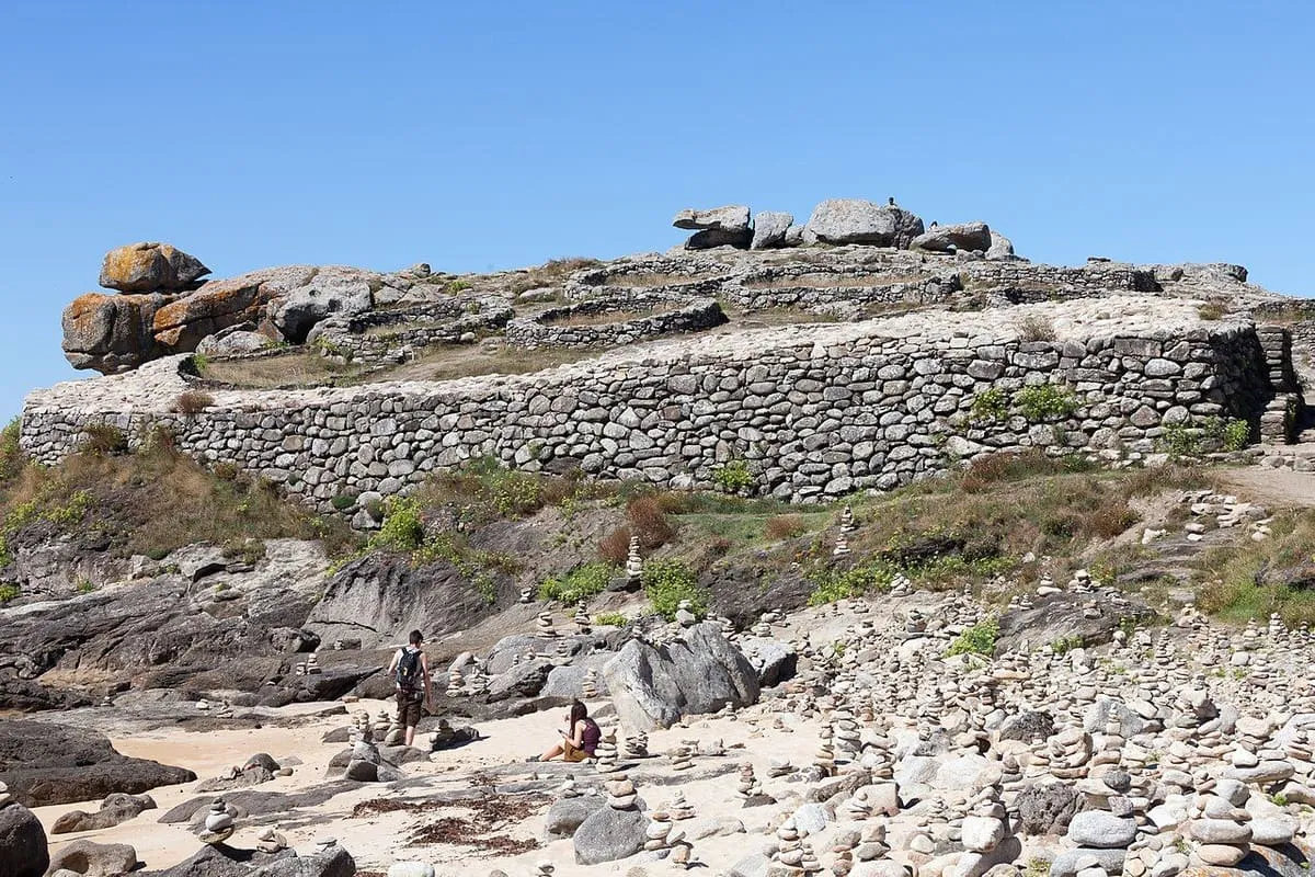 Muralla de piedra del castro sobre la roca, con un gran peñón encima