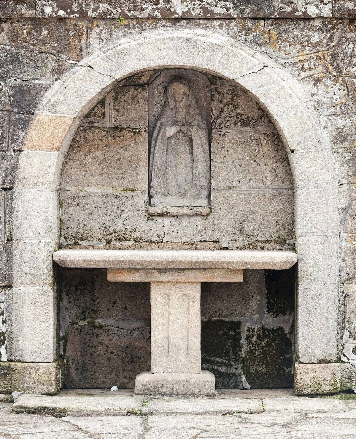 Hornacina con una imagen y un altar de piedra en el atrio de la iglesia de Muros