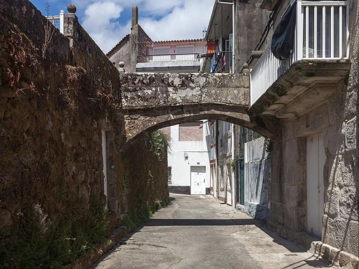 Calle estrecha de Muros con un arco de piedra y balcones corridos