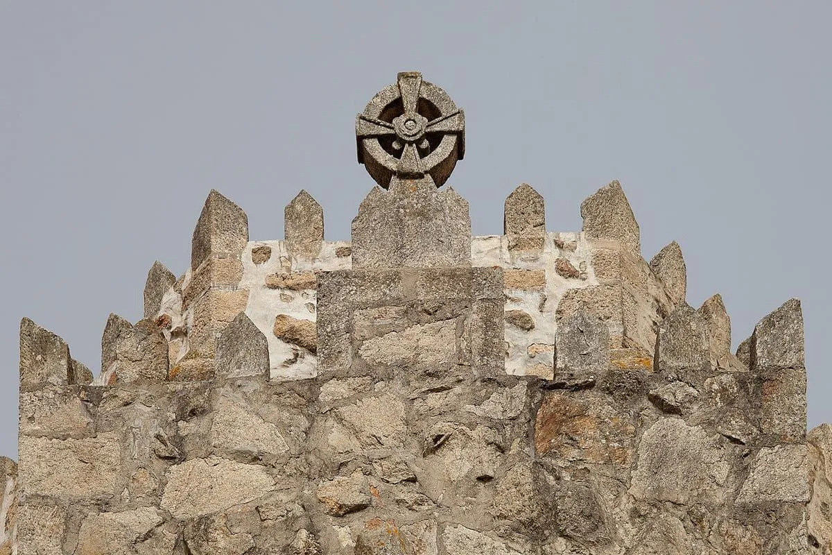 Remate almenado de granito del templo con un rosetón de piedra