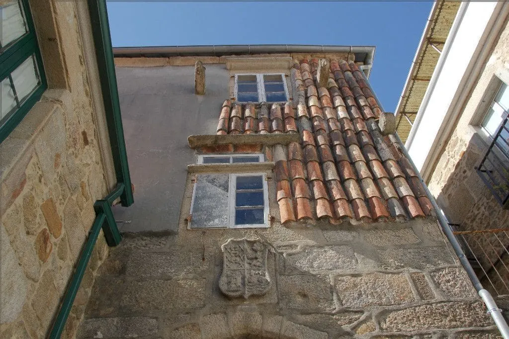 Casa de piedra con escudo y tejado de teja en el casco vello de Noia