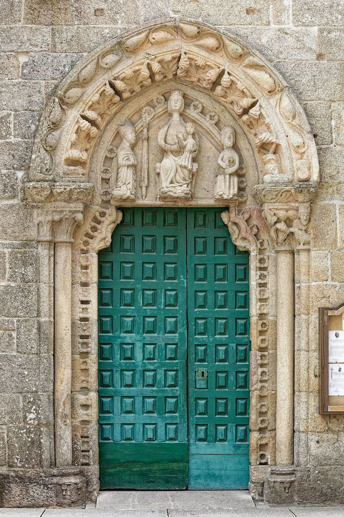Portal lateral con arquivoltas y una puerta verde en San Martiño de Noia