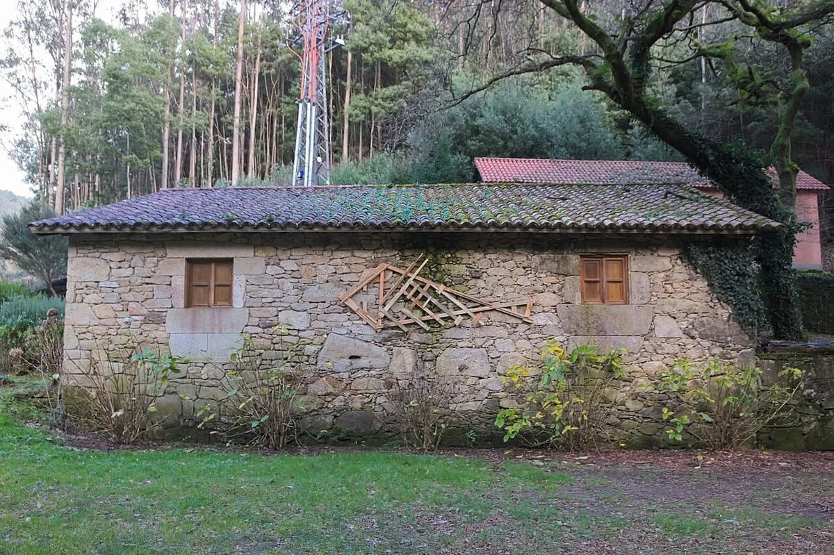 La Casa dos Frades, un edificio de piedra con tejado de teja entre árboles