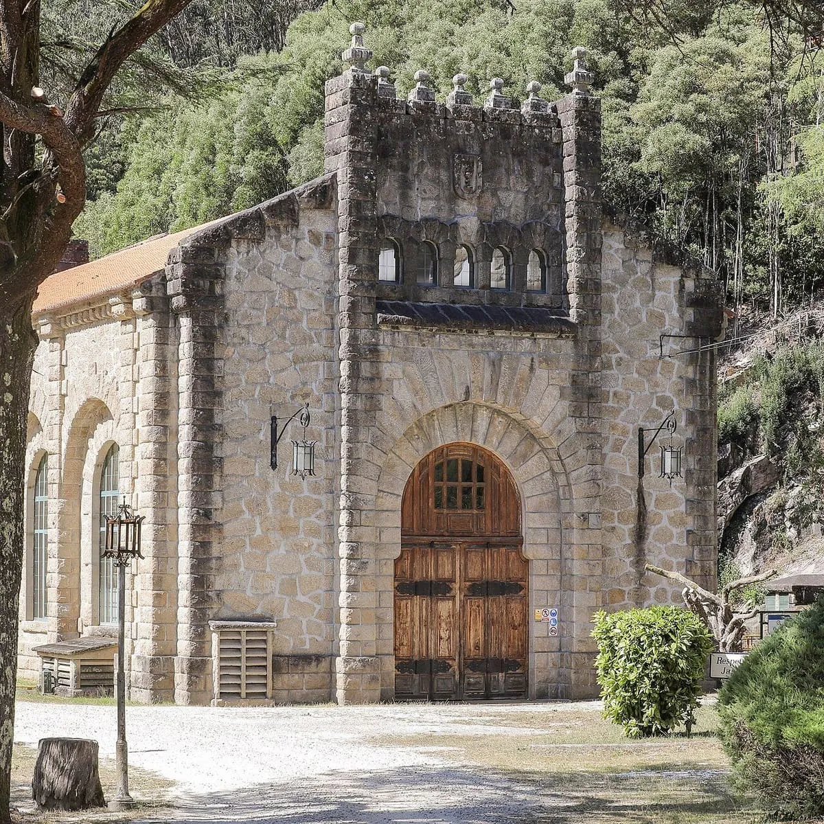 Portada de arco de medio punto de la central del Tambre, con puertas de madera y ventanas altas