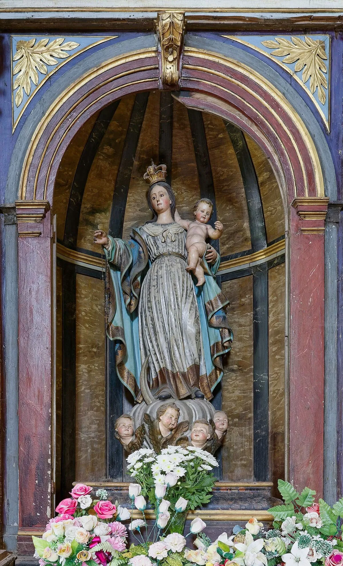 Imagen de la Virgen con el Niño en una hornacina decorada con flores, en Santa María a Nova