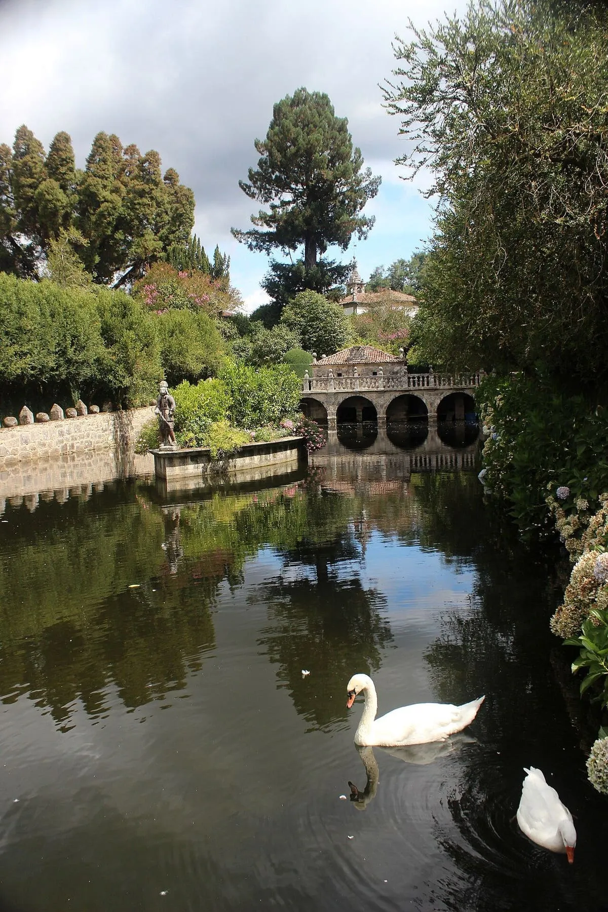 Estanque del jardín del pazo de Oca con un cisne y un puente al fondo