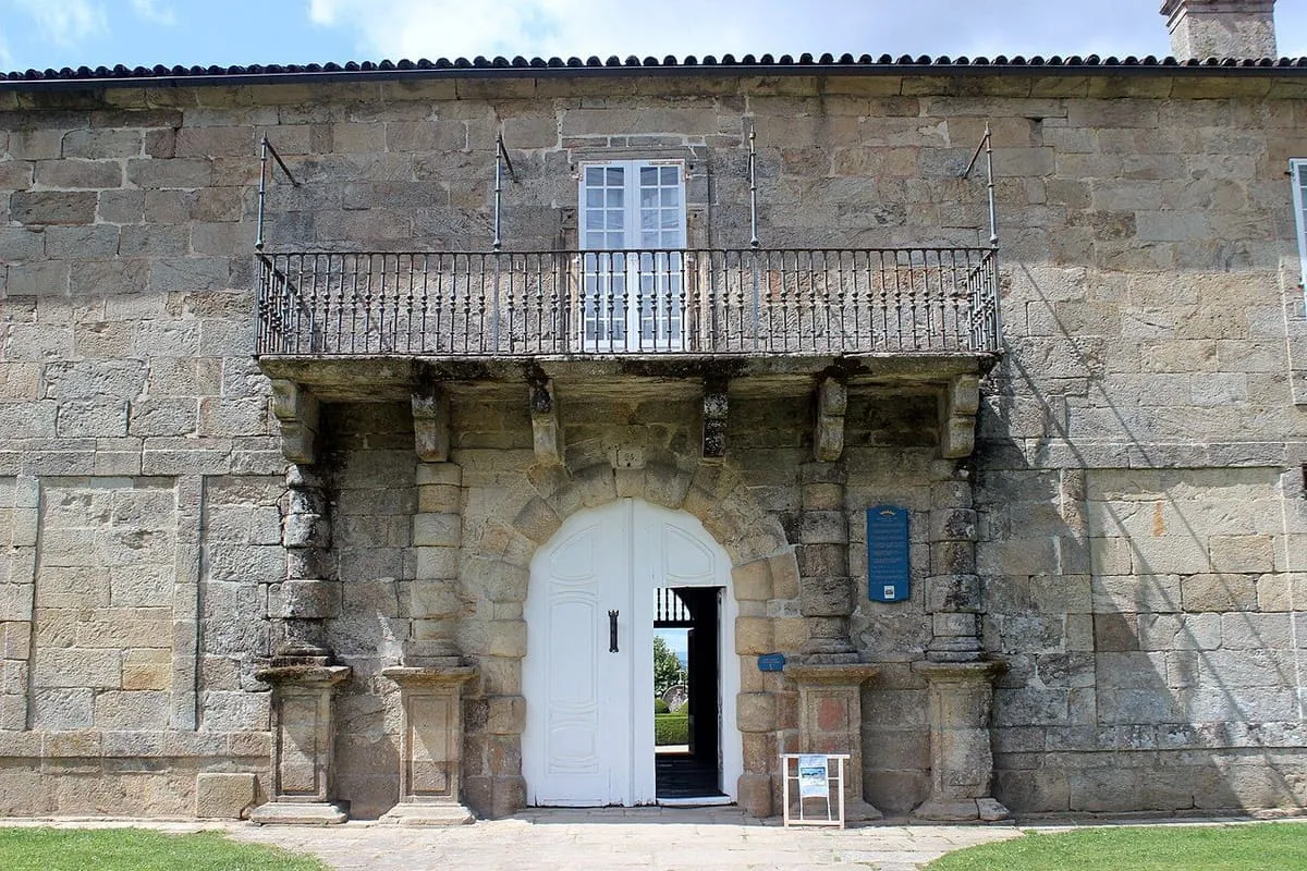 Portal de piedra con balcón de hierro en la fachada del pazo de Oca