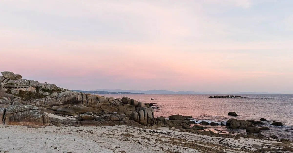 Costa rocosa de San Vicente do Grove al atardecer, con el cielo rosado y el mar en calma