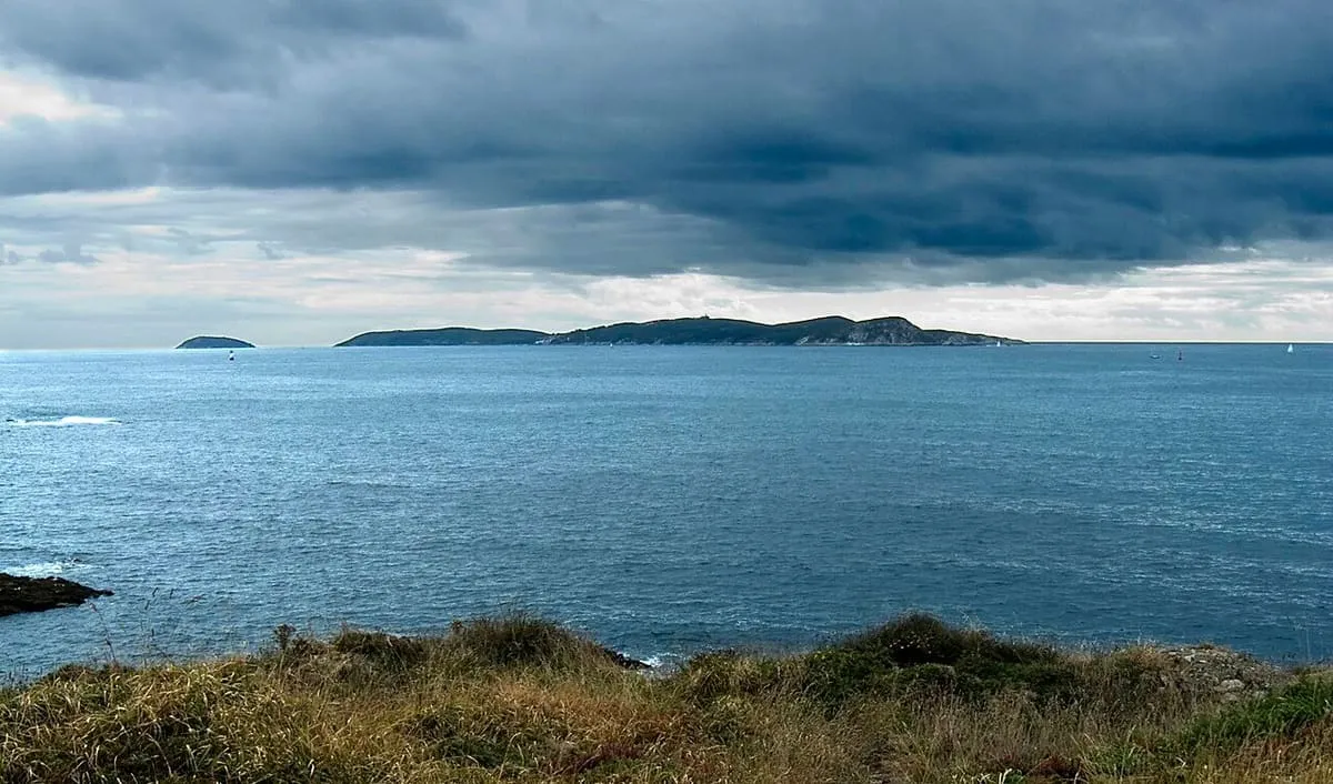Las islas de Ons y Onza vistas desde la costa bajo un cielo tormentoso