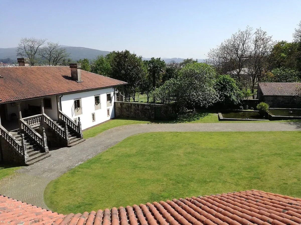 Patio y jardín de la Torre do Monte, con la casa de piedra y un tejado de teja
