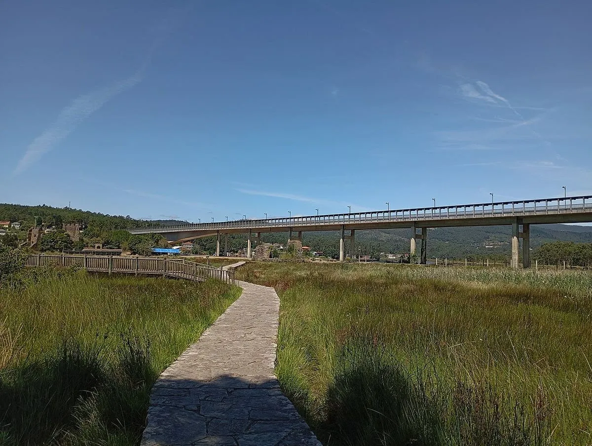 Pasarela de piedra entre las marismas del Ulla, con el puente sobre la ría al fondo