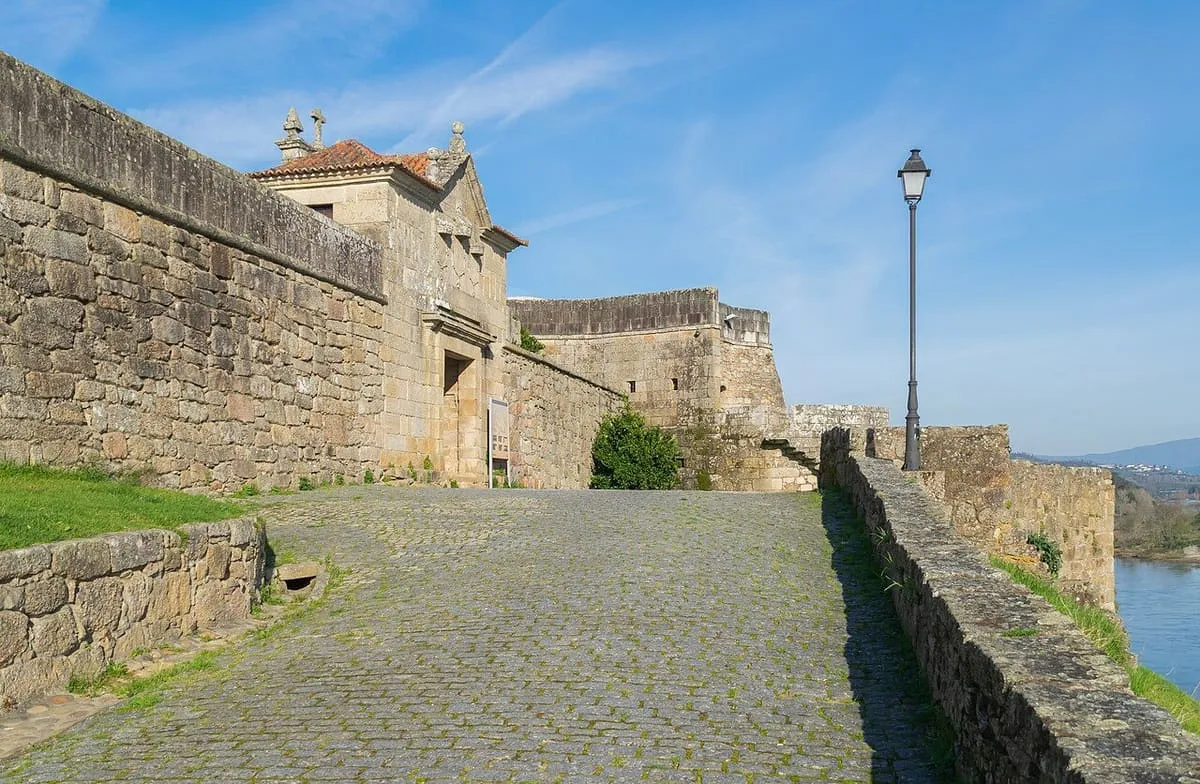 Camino empedrado junto a la muralla de la fortaleza de Salvaterra, con el río a la derecha