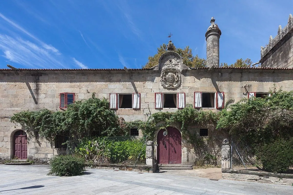 Fachada de piedra del pazo de Vista Alegre, con hiedra y un gran escudo
