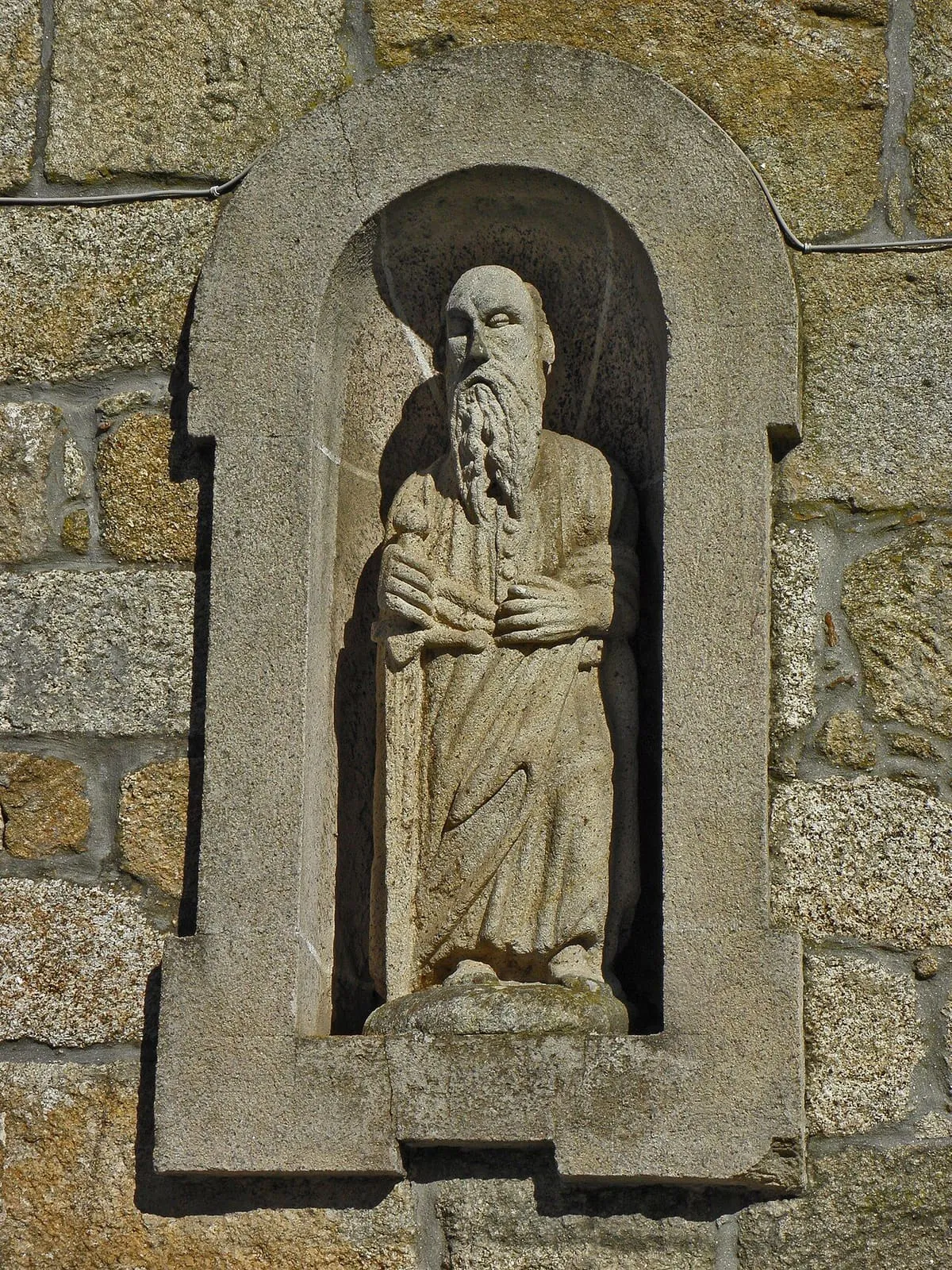 Figura de piedra tallada en un nicho de la fachada de Santiago do Deán